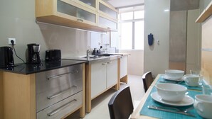 Een moderne keuken met roestvrijstalen apparatuur, houten keukenkastjes en een eethoek met een tafel gedekt voor vier personen.