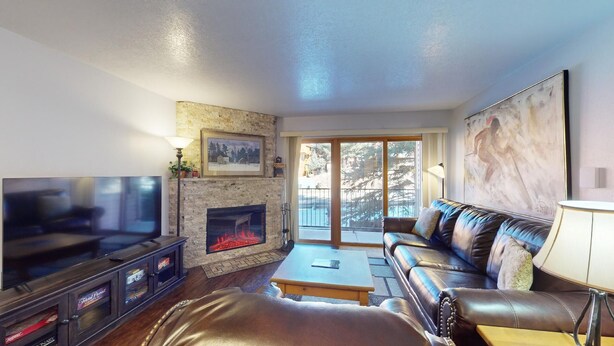 A living room with a fireplace, a sofa, a television, and a large window. - Walk to lifts | Easy Access | Wi-Fi | Mountain Spirits 215 (Angel Fire)