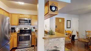 A modern kitchen with stainless steel appliances, wooden cabinets, and a stone accent wall. - Walk to lifts | Easy Access | Wi-Fi | Mountain Spirits 215 (Angel Fire)