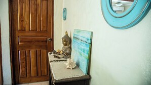 A wooden door, a Buddha statue, a painting, and a mirror on a wall. - Tropical Patio & Garden, Walk to Samara Beach
 (Sámara)