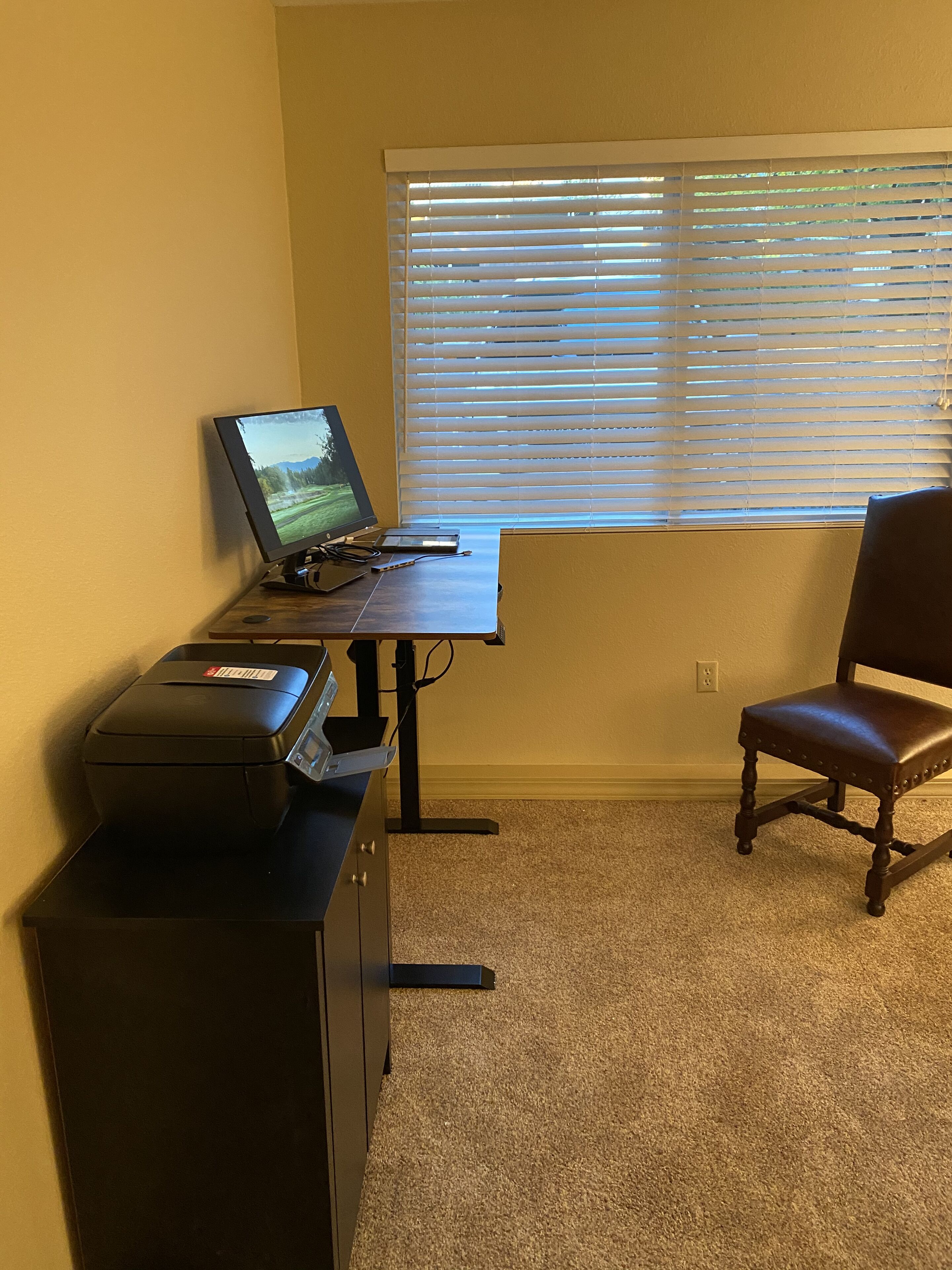 Un espacio de trabajo en casa con escritorio, computadora, impresora y silla.