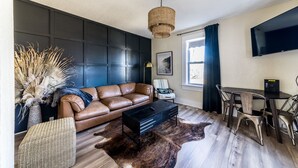 A modern living room with a leather sofa, a coffee table, and a dining area with chairs.