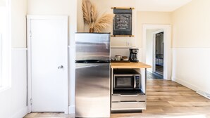 A compact kitchen with a stainless steel refrigerator, a microwave, and a wooden countertop.