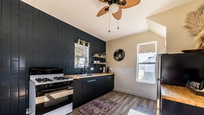 A modern kitchen with dark cabinetry, a gas stove, a built-in oven, and a wooden countertop.