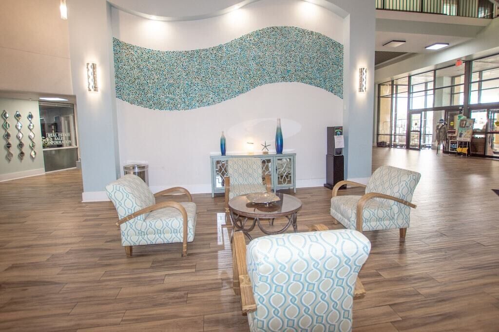A lobby with patterned chairs, a round table, and a decorative wall.