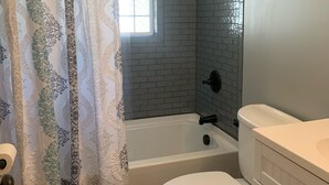 Et badeværelse med bruser, toilet og vask.