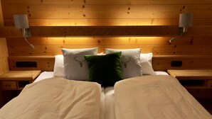 A double bed with two pillows, one green and one white, in a room with wooden walls and a headboard. - Living - vision - well-being ***** with attention to detail! (Reit im Winkl)