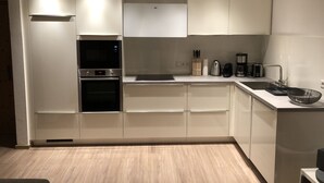 A modern kitchen with white cabinetry, a built-in oven, microwave, and a coffee maker. - Living - vision - well-being ***** with attention to detail! (Reit im Winkl)