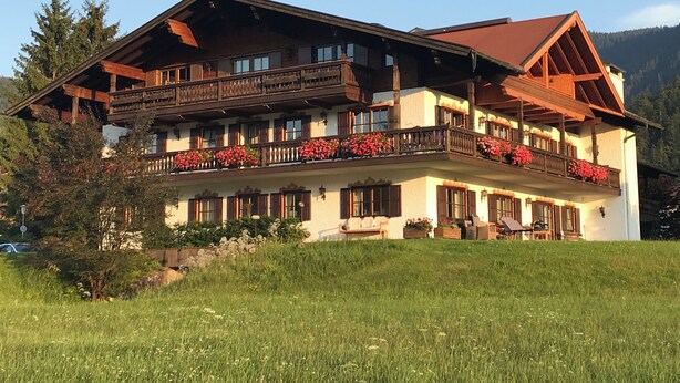 A two-story building with wooden balconies and flower boxes. - Living - vision - well-being ***** with attention to detail! (Reit im Winkl)