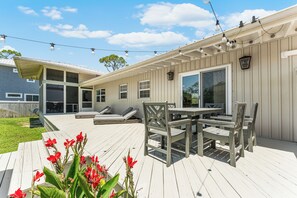 A covered outdoor patio with a table and chairs, a sliding glass door, and string lights.