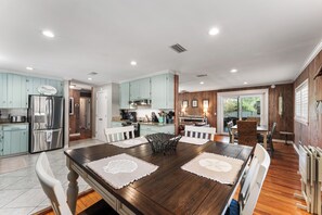 A spacious kitchen with modern appliances, a dining area with a large wooden table, and a cozy seating area with a fireplace.