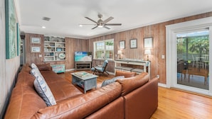 A living room with a brown leather sofa, a television, and wooden panel walls. -  Pet Friendly Cape San Blas Getaway Near the Gulf (Cape San blas)