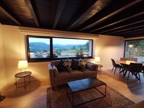 Relax in this inviting living room with a scenic valley view, a comfortable sofa, and a dining area.