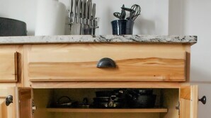 Eine Küche mit Holzausstattung, einer Marmorarbeitsplatte und verschiedenen Küchengeräten.