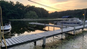 Eine hölzerne Steg, der sich in ruhiges Wasser erstreckt, mit Booten, die am Ende festgemacht sind.