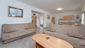 Un salon moderne avec deux canapés, une table basse en bois et une cuisine en arrière-plan.