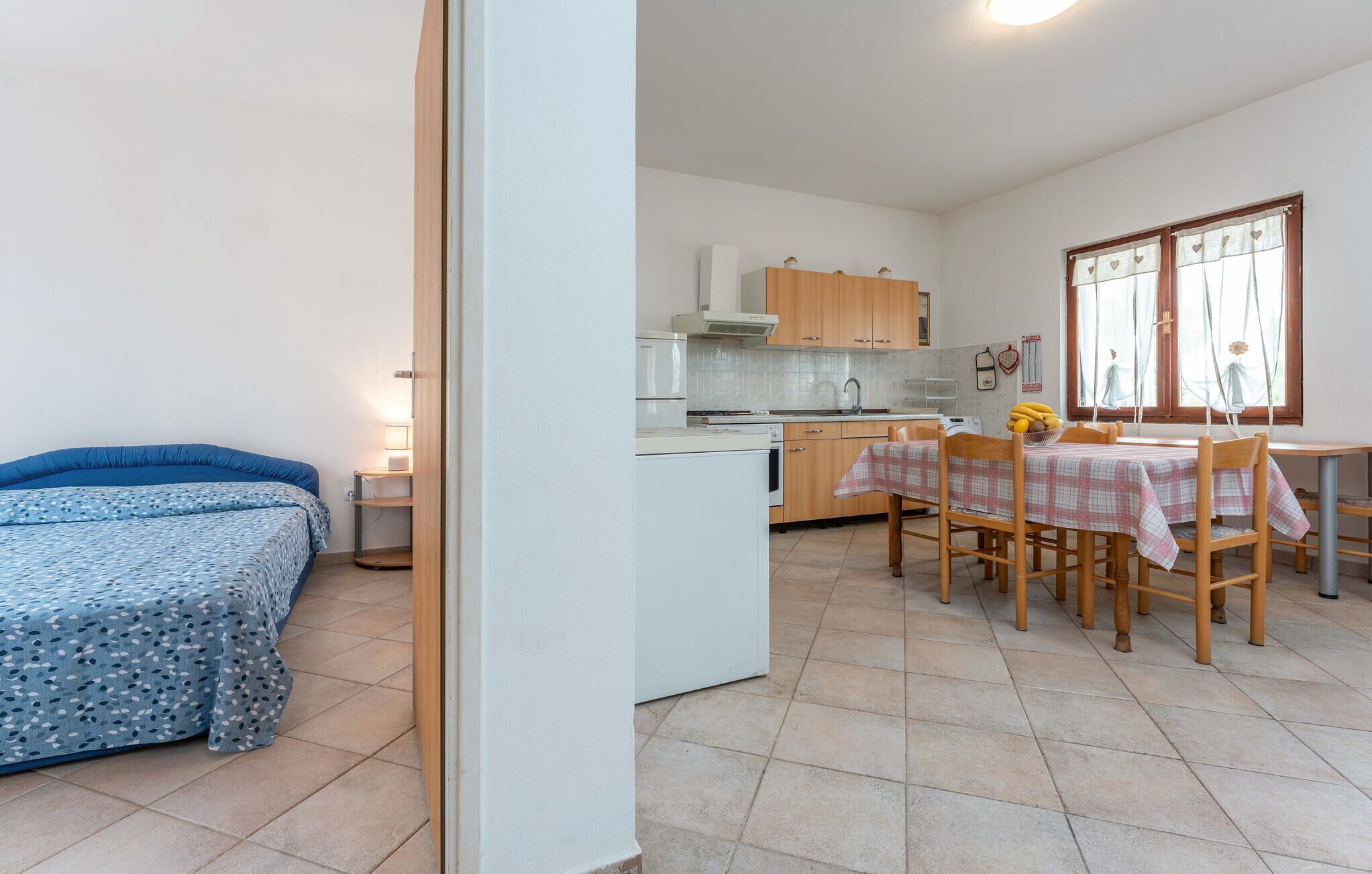 Une pièce compacte comprenant un lit, une petite kitchenette et un coin repas avec une table et des chaises.