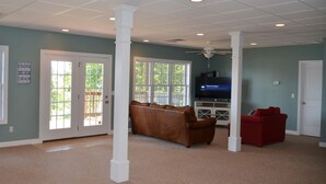 A spacious living room with a brown leather couch, a red sofa, and a television.