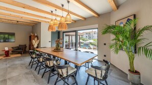 A dining area with a wooden table and chairs, a hanging light fixture, and a large potted plant. - Gorgeous home in Biograd na moru with sauna (Biograd na moru)