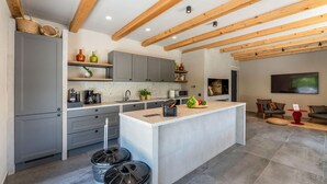 A modern kitchen with grey cabinets, a central island, and wooden beams on the ceiling. There are trash bins and a coffee maker on the counter. - Gorgeous home in Biograd na moru with sauna (Biograd na moru)