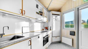 Cuina moderna amb armaris blancs, un vàter d'acer inoxidable i un forn encastrat.
