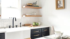 Une cuisine moderne avec des meubles noirs, un plan de travail blanc et des accessoires dorés.