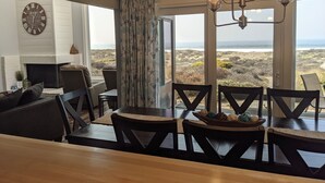 A dining area with a view of the ocean, a fireplace, and a clock on the wall.