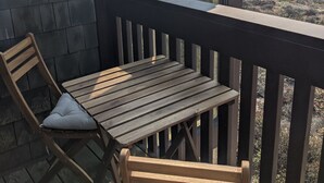 A wooden deck with a table and chairs, overlooking a coastal landscape.