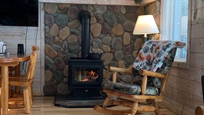 A cozy cabin interior with a stone fireplace, wooden furniture, and a television. - UP LIVING on Big Manistique Lake at its finest. 200 ft of private lake frontage. (Curtis)