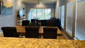 A dining area with a granite table, dark upholstered chairs, and a ceiling fan.