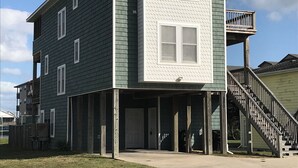 A two-story house with a front porch, a balcony, and a staircase leading to the second floor. - SPACIOUS FAMILY FRIENDLY HOME, 300 STEPS TO BEACH, PRIVATE POOL/HOT TUB (Kill Devil Hills)