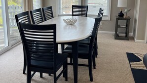 A dining area with a round table, six chairs, and a decorative bowl. - SPACIOUS FAMILY FRIENDLY HOME, 300 STEPS TO BEACH, PRIVATE POOL/HOT TUB (Kill Devil Hills)