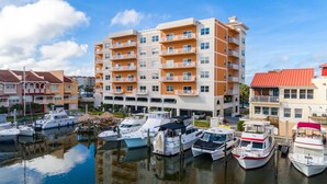 A marina with multiple boats docked, surrounded by multi-story buildings with balconies.