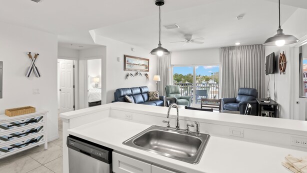 A modern kitchen with a central island, white cabinetry, and a built-in dishwasher.