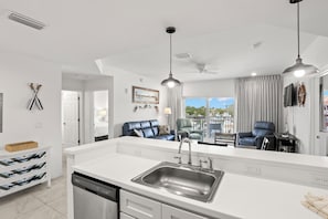 Una cocina moderna con una isla central, muebles blancos y un lavavajillas integrado.