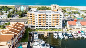 A hotel with multiple floors, a marina with boats, and a beach in the background.