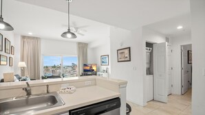 Ett modernt kök med diskmaskin, diskho och ett fönster med gardiner.