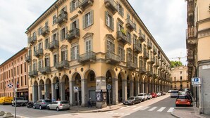 A multi-story building with balconies, a pedestrian crossing, and parked cars. - GuestHost - ★ Apt in the very center! 500 meters from Porta Nuova ★ (Torino)