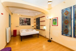 A bedroom with a bed, a radiator, a red cabinet, a framed picture, a floor lamp, and a stained glass window. - GuestHost - ★ Apt in the very center! 500 meters from Porta Nuova ★ (Torino)