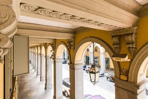 An interior corridor with classical arches and columns, leading to an outdoor street view.