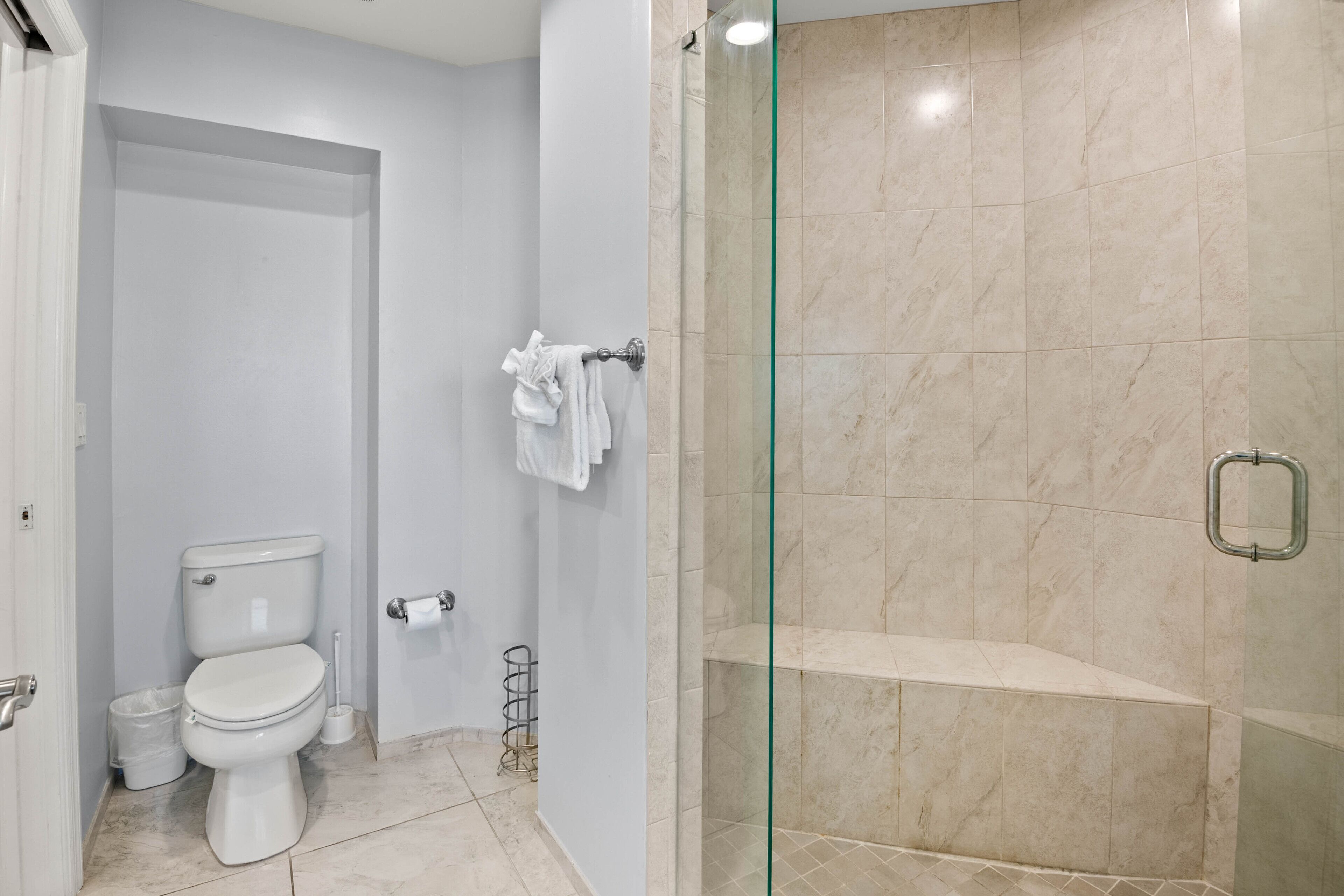 A bathroom with a toilet, a glass shower enclosure, and a towel rack.