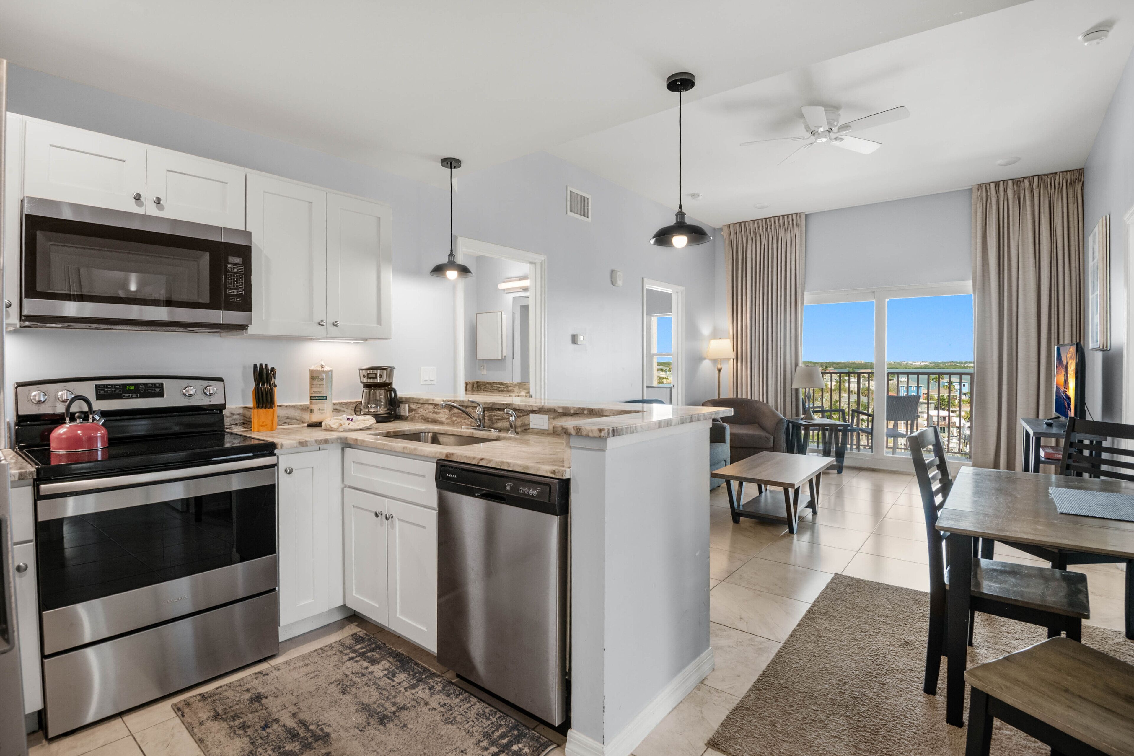 A modern kitchen with stainless steel appliances, a dishwasher, and a dining area with a view.