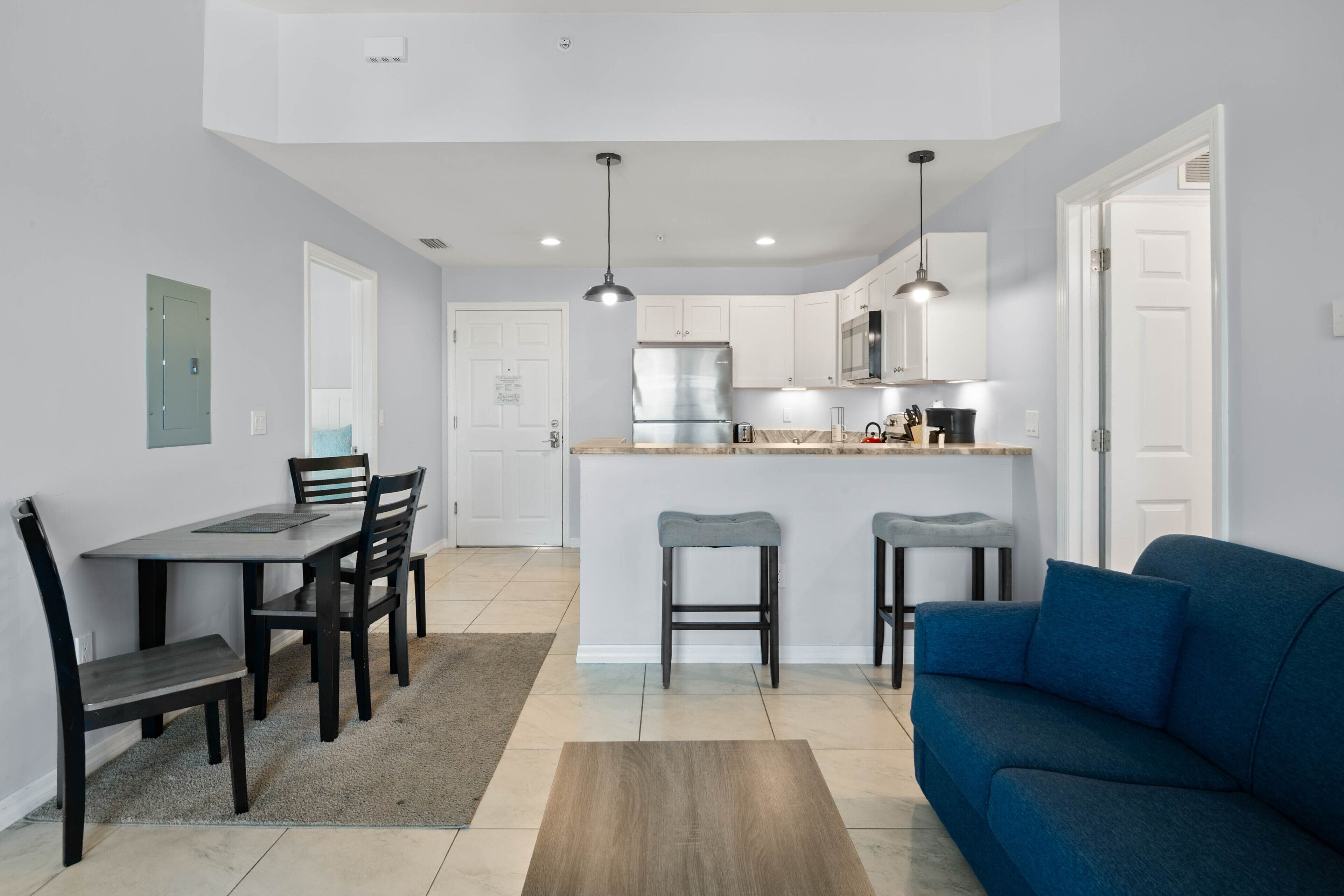 A modern kitchen with white cabinets, a central island, and bar stools.