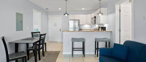 A modern kitchen with white cabinets, a central island, and bar stools.