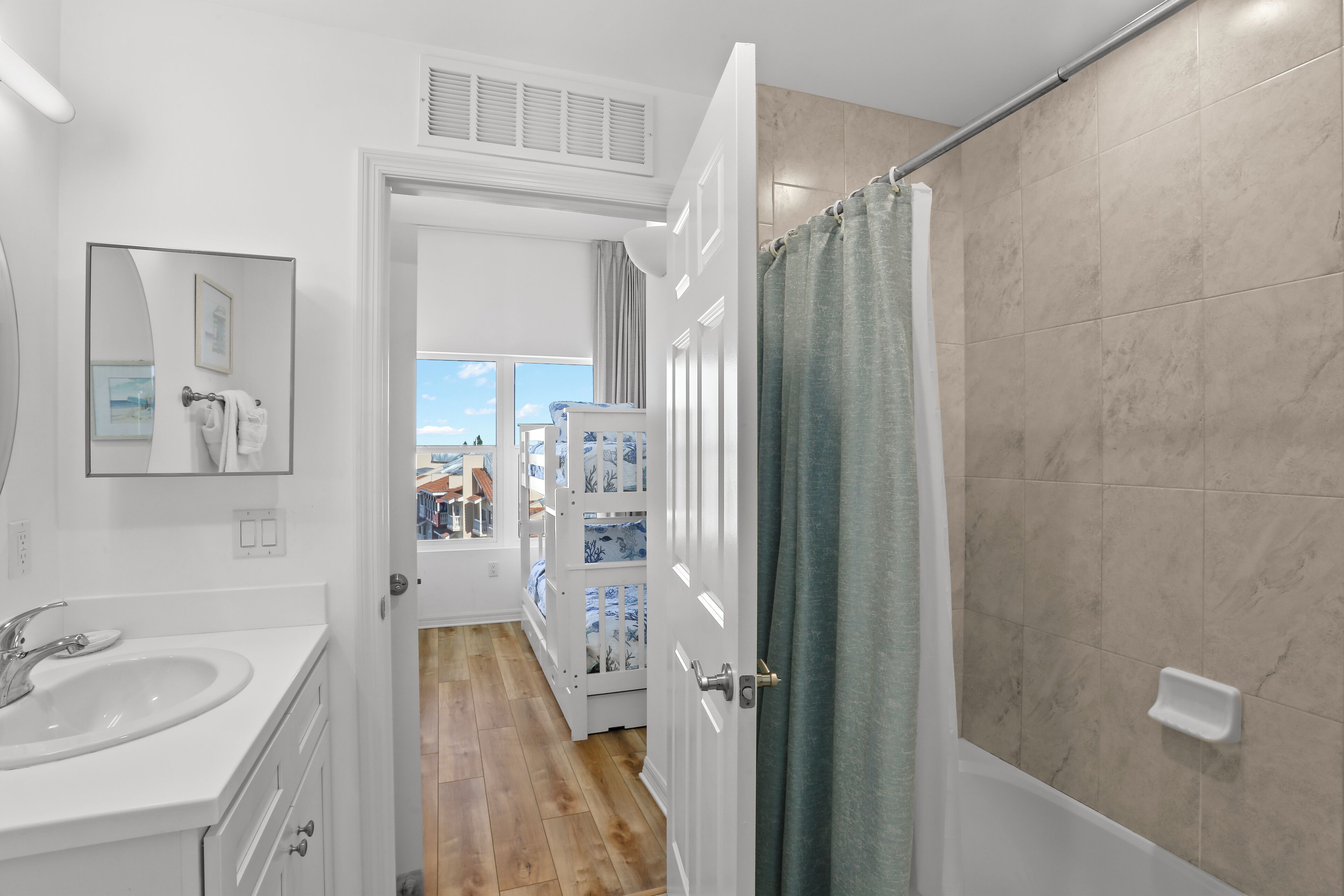 Un baño con lavamanos blanco, espejo y cortina de ducha.