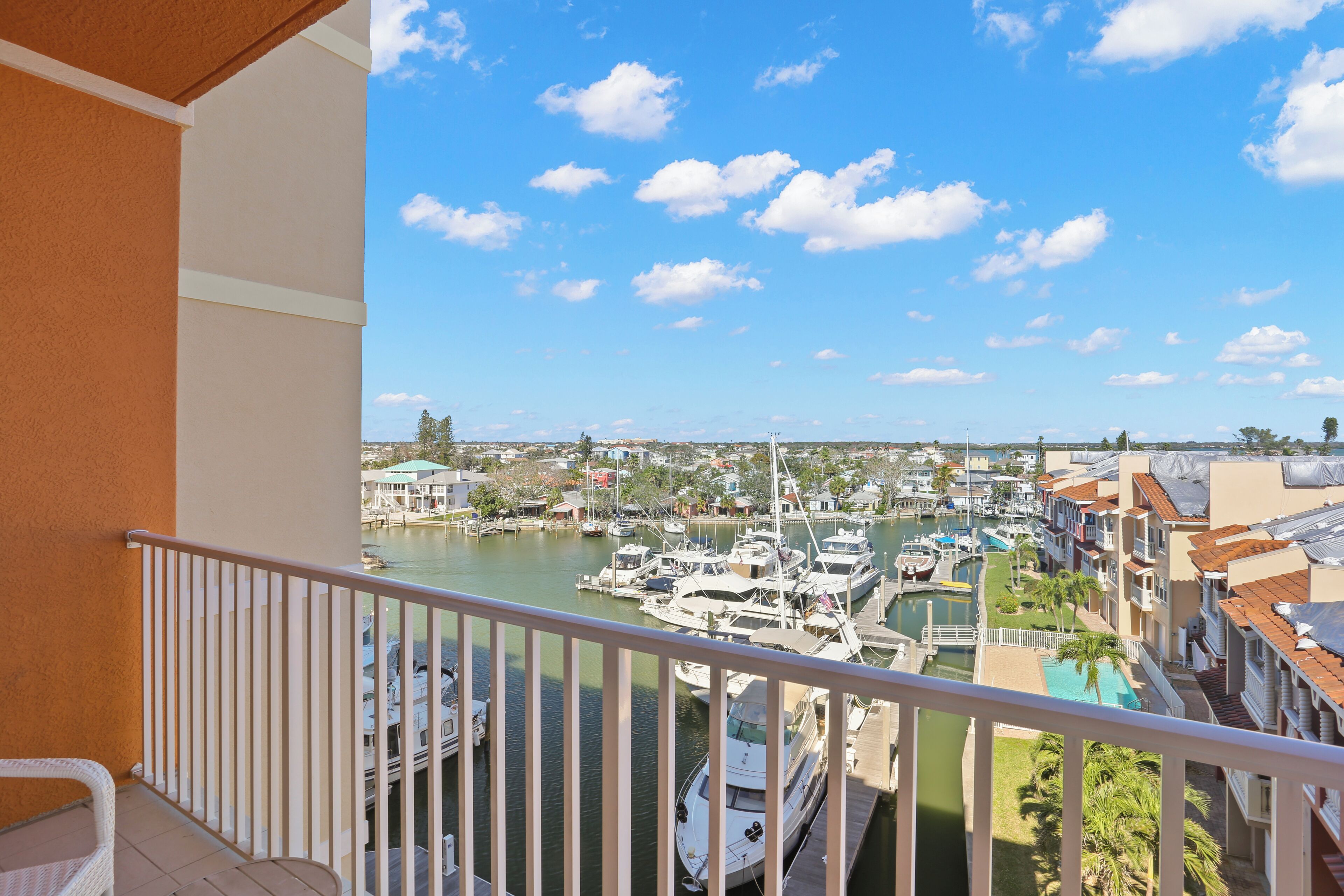 A balcony with a view of a marina, boats, and a town in the background.