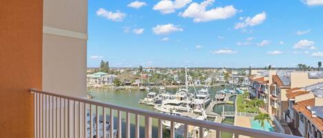 A balcony with a view of a marina, boats, and a town in the background.