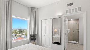 A hotel room with a large window, a bed, a door leading to a bathroom, and a view of the outside. - 🐾 Madeira Bay Resort I #1608 – Pet-Friendly, Professionally Sanitized & Steps from the Shore (Madeira Beach)
