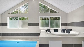 Ein modernes Badezimmer mit einer Badewanne, großen Fenstern und einem Pool.