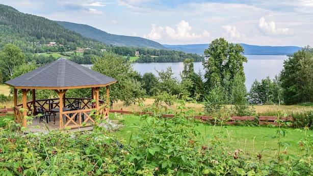 Un belvédère doté d’un toit et de sièges, offrant une vue sur un lac et des collines.